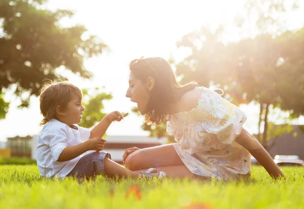 彼女の息子が公園でヨーグルトを食べることで美しい若い母親. — ストック写真