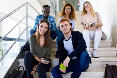 Kamera bir üniversitede bakarak mutlu genç öğrenci grubu.