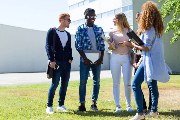 Grupa szczęśliwy młodych studentów mówienia w uczelni. — Zdjęcie stockowe