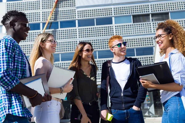 Gäng glada unga studenter talar i ett universitet. — Stockfoto
