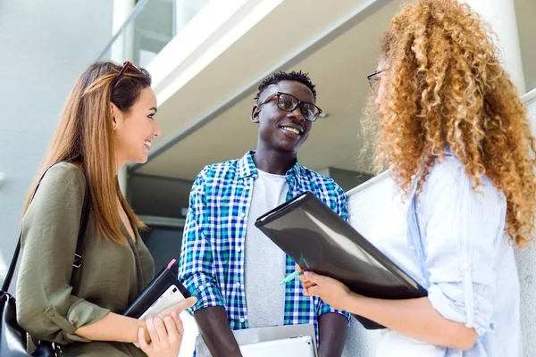 Grupa szczęśliwy młodych studentów mówienia w uczelni. — Zdjęcie stockowe