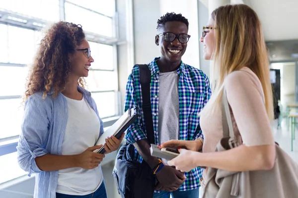 Gäng glada unga studenter talar i ett universitet. — Stockfoto