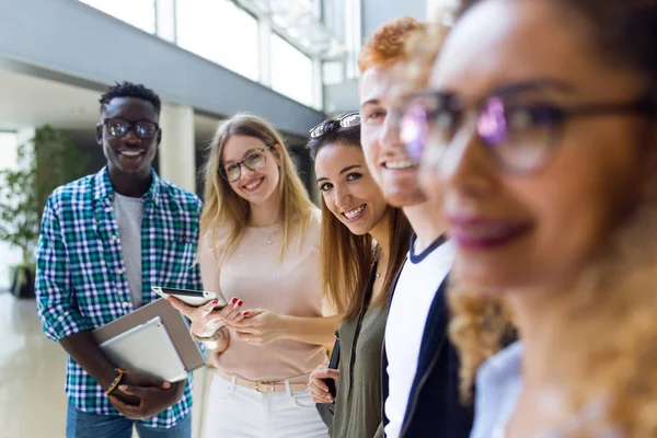 Groupe de jeunes étudiants heureux regardant la caméra dans une université . — Photo