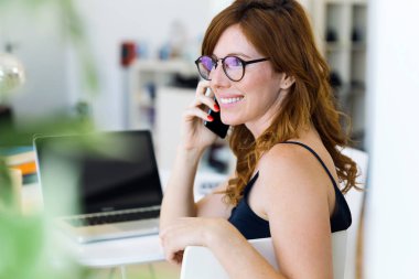 Cep telefonu ile evde çalışan güzel genç kadın.