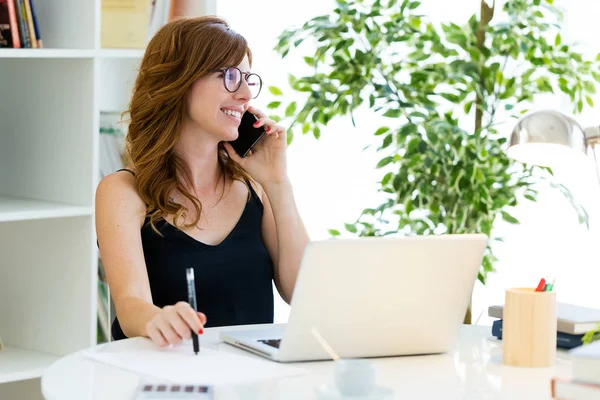 Cep telefonu ile evde çalışan güzel genç kadın. — Stok fotoğraf