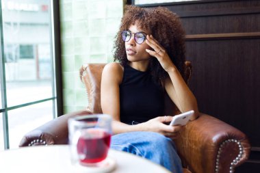 Cep telefonu kafede kullanan güzel genç kadın.