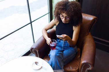 Cep telefonu kafede kullanan güzel genç kadın.