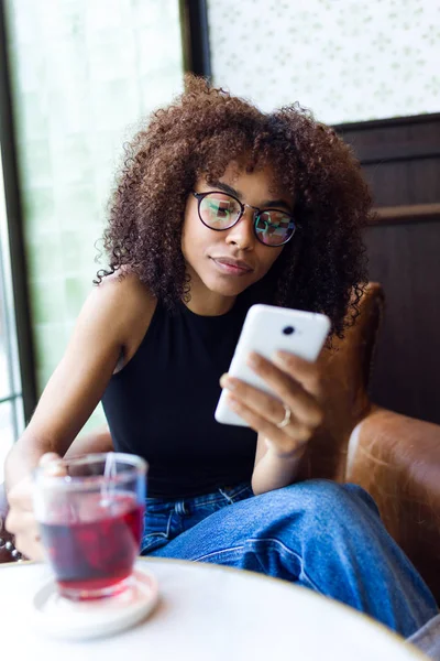 Красива молода жінка використовує свій мобільний телефон в кафе . — стокове фото