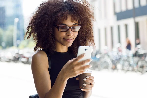 Bella giovane donna che utilizza il suo telefono cellulare in strada . — Foto Stock