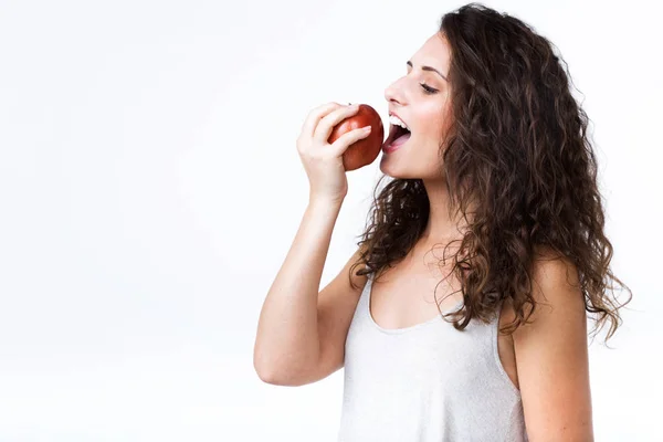 Mulher bonita comendo maçã vermelha sobre fundo branco . — Fotografia de Stock