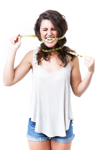 Young woman biting tape measure over white background. — Stock Photo, Image