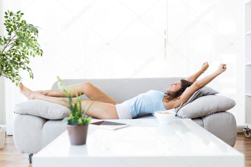 beautiful young woman stretching in sofa after wake up.