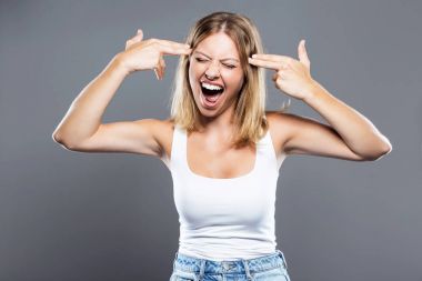 Onun kafasına gri arka plan üzerinde çekim bir jest yapma güzel genç kadın.