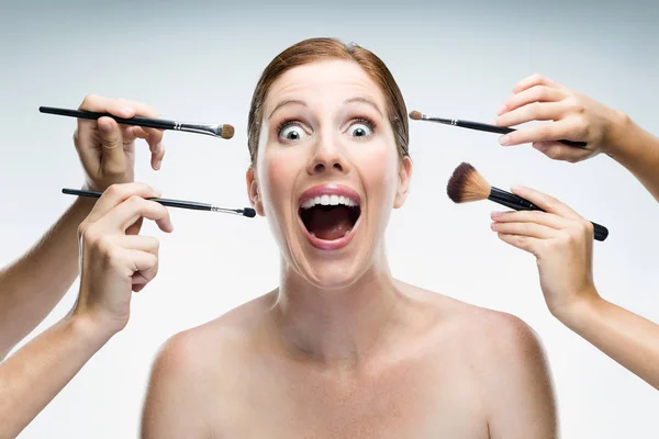 Muitas mãos aplicando maquiagem para mulher glamour sobre fundo branco . — Fotografia de Stock
