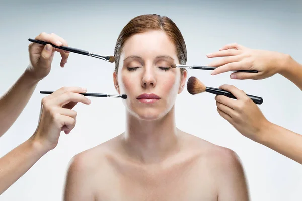 Many hands applying make-up to glamour woman over white background. — Stock Photo, Image