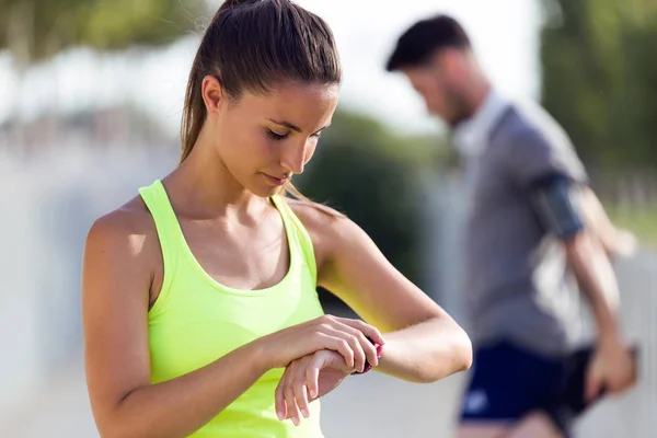 Deportiva joven mujer buscando su reloj inteligente en la calle . — Foto de Stock