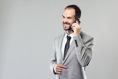 Onun cep telefonu gri arka plan üzerinde kullanan iş genç adam.