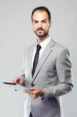 İş genç adam onun dijital tablet gri arka plan üzerinde kullanma