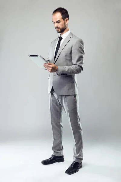İş genç adam onun dijital tablet gri arka plan üzerinde kullanma — Stok fotoğraf