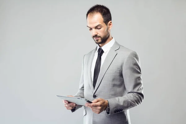 Business giovane uomo utilizzando il suo tablet digitale su sfondo grigio — Foto Stock