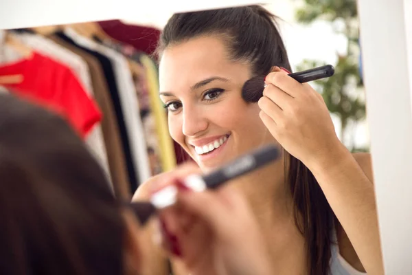 Vacker ung kvinna att göra make-up nära spegeln hemma. — Stockfoto