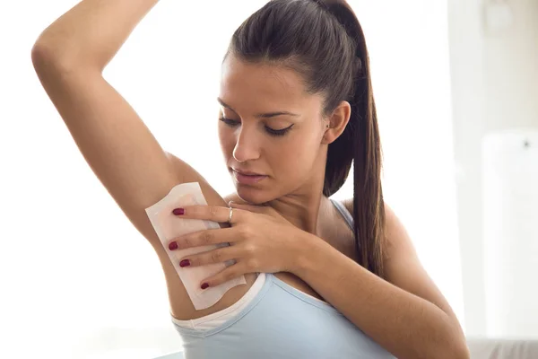 Beautiful young woman shaving her armpit with wax in the bathroo — Stock Photo, Image