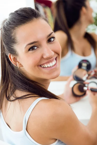 Hermosa joven mujer haciendo maquillaje cerca del espejo en casa . —  Fotos de Stock