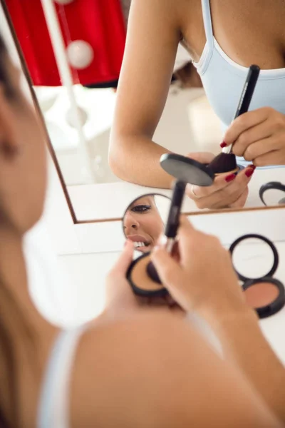 Mulher bonita fazendo maquiagem perto do espelho em casa . — Fotografia de Stock