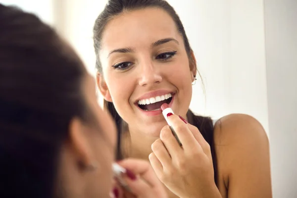 Vacker ung kvinna att göra make-up nära spegeln hemma. — Stockfoto