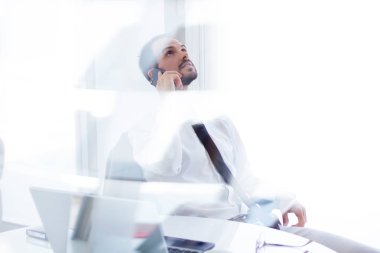 Dizüstü bilgisayar ve cep telefonu ofisteki çalımakta yakışıklı genç.