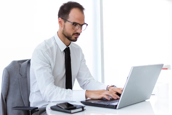 Schöner junger Mann arbeitet mit Laptop im Büro. — Stockfoto