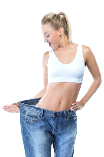 Beautiful young woman wearing big jeans over white background. — Stock Photo, Image