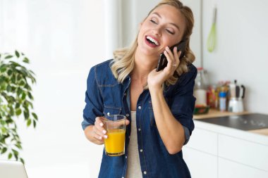 Mutfakta cep telefonu kullanan güzel genç kadın.