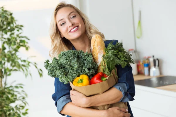 Bolsa de compras bela jovem mulher com legumes em casa . — Fotografia de Stock
