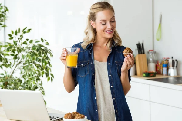 Vacker ung kvinna som äter frukost i köket. — Stockfoto