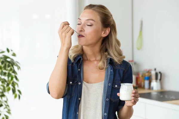 Mulher bonita comendo iogurte em casa . — Fotografia de Stock