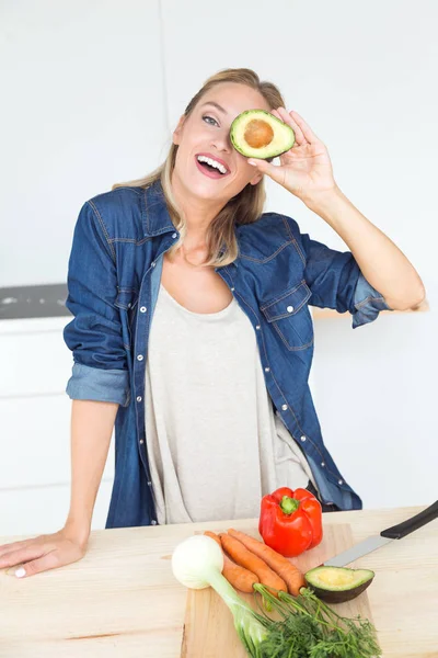 Hermosa joven sosteniendo aguacate en la cocina . — Foto de Stock