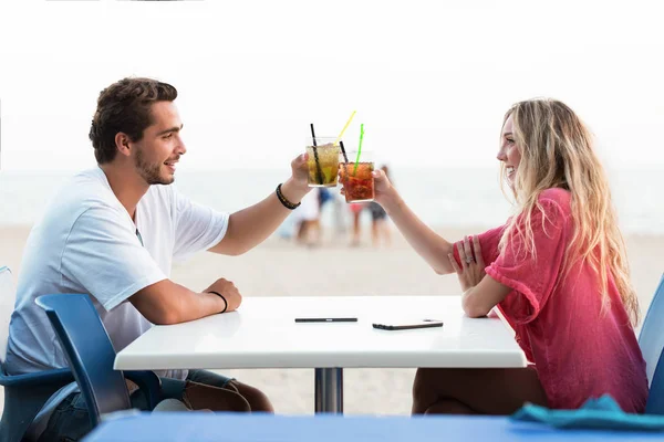 Beau jeune couple buvant un rafraîchissement sur la plage . — Photo