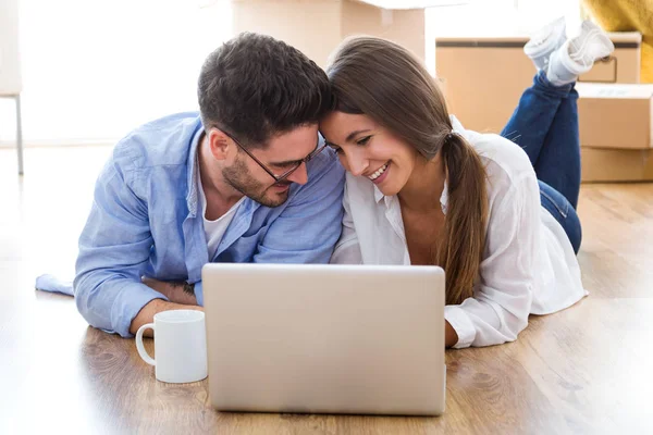 Couple utilisant un ordinateur portable dans leur nouvelle maison . — Photo