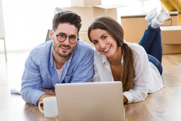 Pareja usando el ordenador portátil en su nuevo hogar . — Foto de Stock