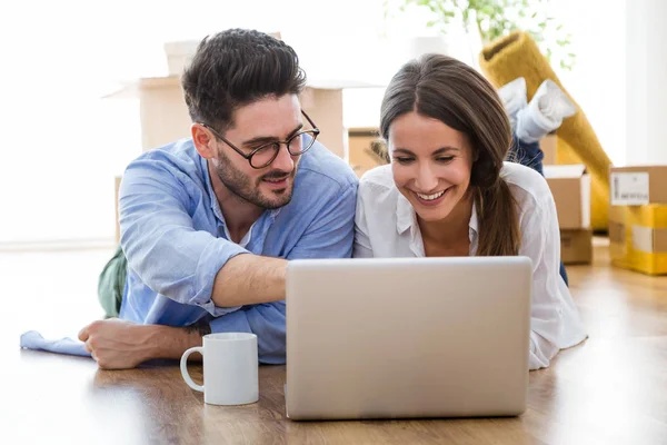 Ehepaar nutzt Laptop im neuen Zuhause. — Stockfoto