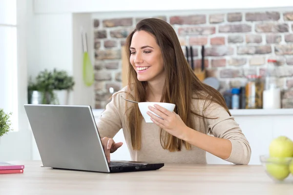 Donna che usa il suo computer portatile mentre mangia — Foto Stock