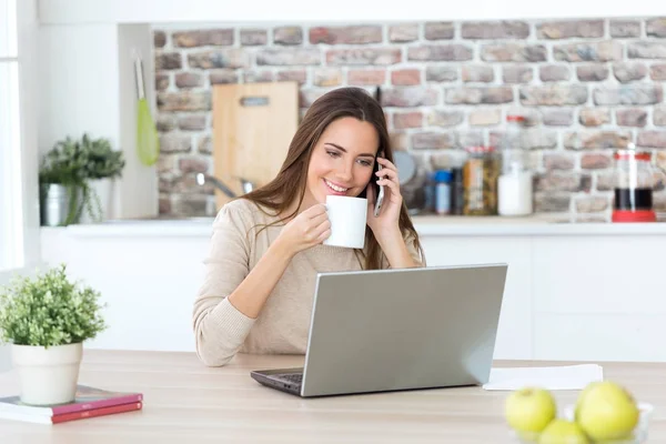 Mujer usando el ordenador portátil y hablando por teléfono —  Fotos de Stock