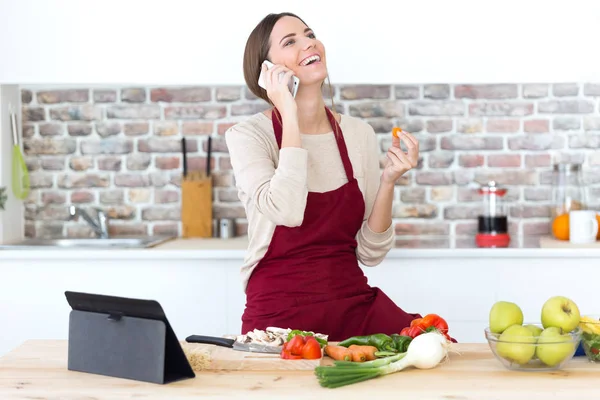 Mujer cocinar y hablar en el móvil — Foto de Stock