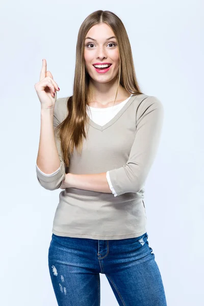 Hermosa joven mujer apuntando hacia arriba sobre fondo blanco . — Foto de Stock