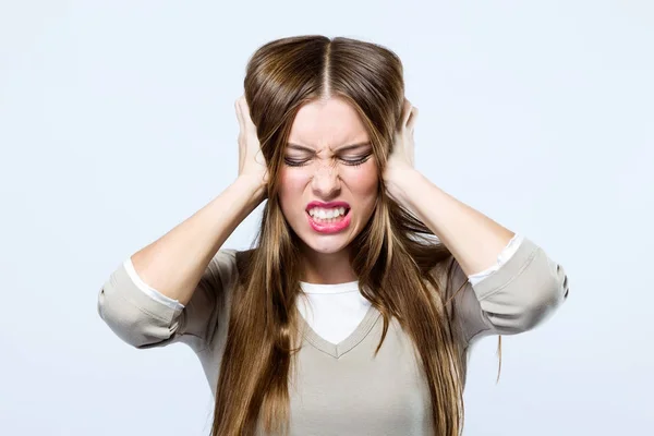 Beautiful young woman covering her ears over gray background. — Stock Photo, Image