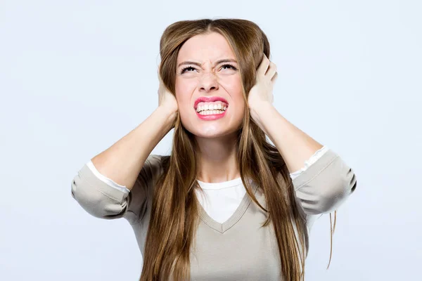 Beautiful young woman covering her ears over gray background. — Stock Photo, Image