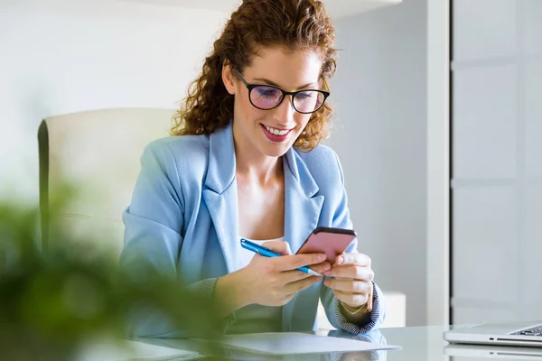 Beautiful young businesswoman using her mobile phone in the office. — Stock Photo, Image