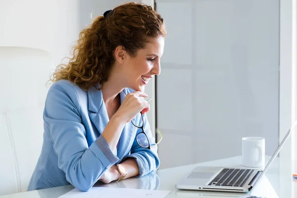 Mooie zakenvrouw werken met haar laptop in het kantoor. — Stockfoto