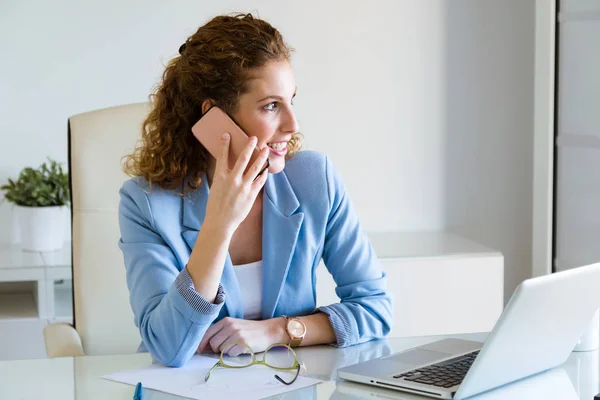 Mooie jonge zakenvrouw met behulp van haar mobiele telefoon in het kantoor. — Stockfoto